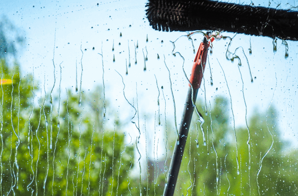 Professional window-cleaning brush removing streaks from a residential glass window